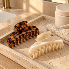Tortoiseshell and cream claw clips on a travertine vanity tray